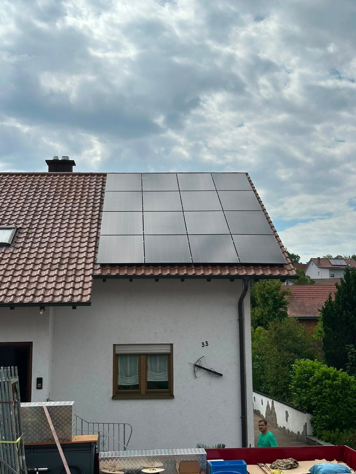 Wohnhaus mit rotem Ziegeldach und einem Feld schwarzer Solarmodule