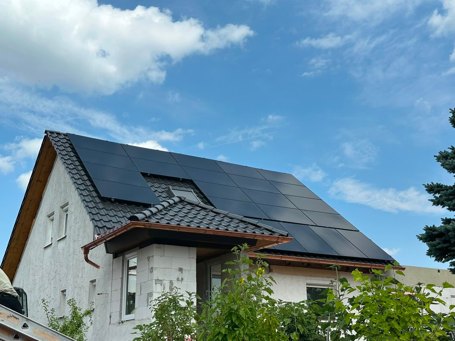 Wohnhaus mit dunklem Dach, die Solarmodule sind um eine Dachgaube herum verlegt